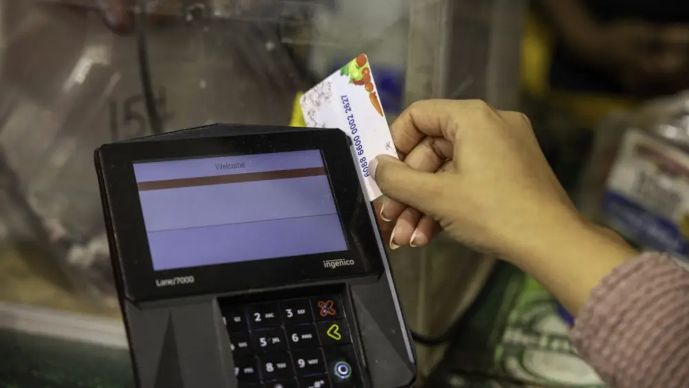 A shopper who receives SNAP benefits slides an EBT card at a checkout counter in a Washington, D.C., grocery store in December 2024. (Photo by U.S. Department of Agriculture)