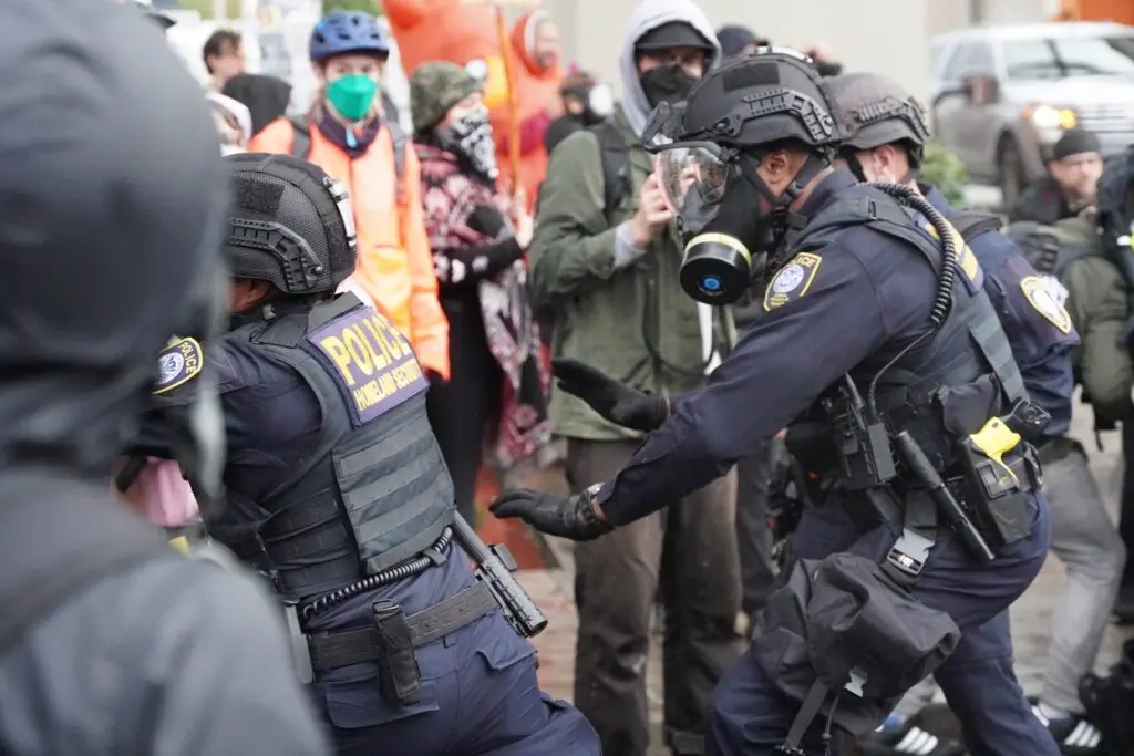 Department of Homeland Security police, along with other federal police, push protestors at the Immigration and Customs Enforcement facility south of downtown Portland on Sunday, Oct. 12, 2025. (Photo by Alex Baumhardt/Oregon Capital Chronicle)