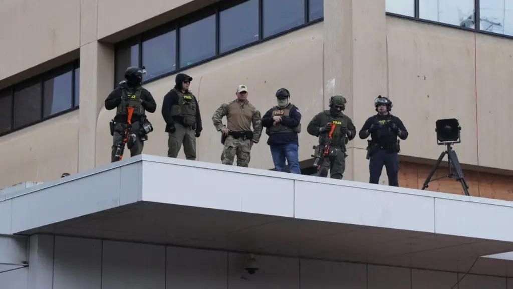Federal officers with pepper-ball guns look down at protestors at the ICE facility south of downtown Portland on Sunday, Oct. 12, 2025. (Photo by Alex Baumhardt/Oregon Capital Chronicle)