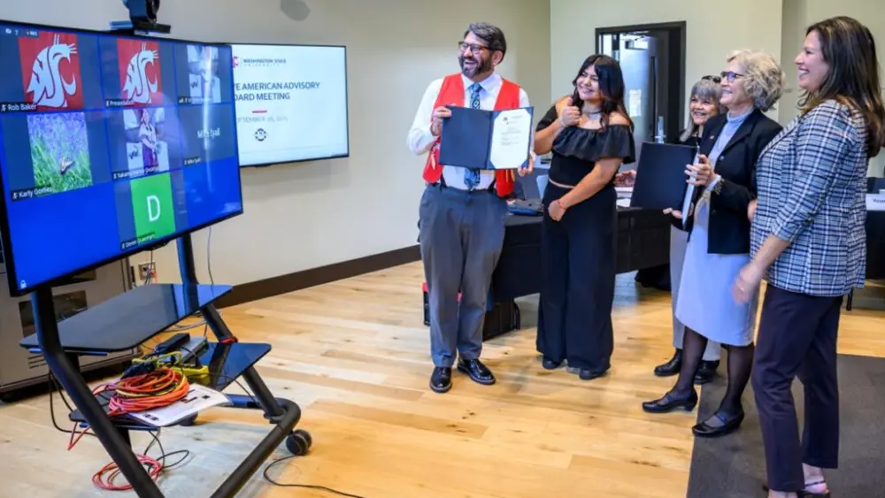Ryan Booth, a faculty member with the Department of History who is an enrolled member of the Upper Skagit Indian Tribe, shows off the signed memorandum of understanding to members of the tribe attending the signing event virtually (photo by Robert Hubner, WSU Photo Services).