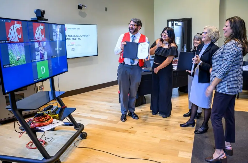 Ryan Booth, a faculty member with the Department of History who is an enrolled member of the Upper Skagit Indian Tribe, shows off the signed memorandum of understanding to members of the tribe attending the signing event virtually (photo by Robert Hubner, WSU Photo Services).