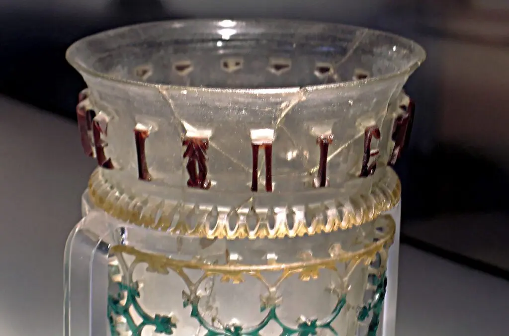 Glass openwork vessel from 300–350 CE with inscription and symbol. Inscription: ΠΙΕ ΖΗCΑΙC ΚΑΛWC ΑΕΙ (Drink, may you live well always!) (photo courtesy of Hallie G. Meredith).