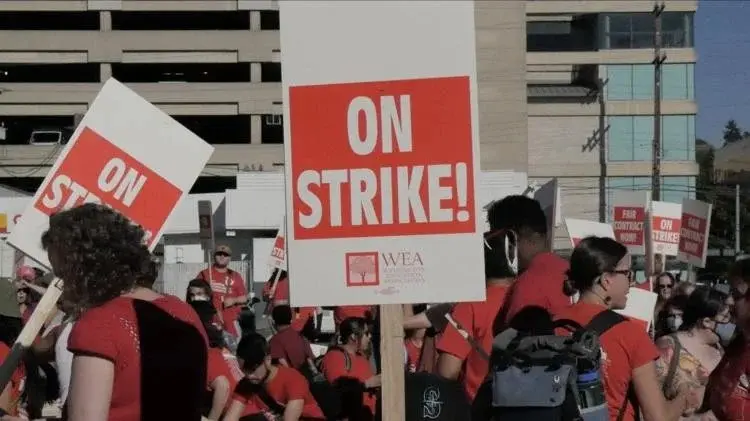 A sign reading "On Strike" is held by a participant during a Seattle teacher strike. Photo: Spencer Pauley / The Center Square