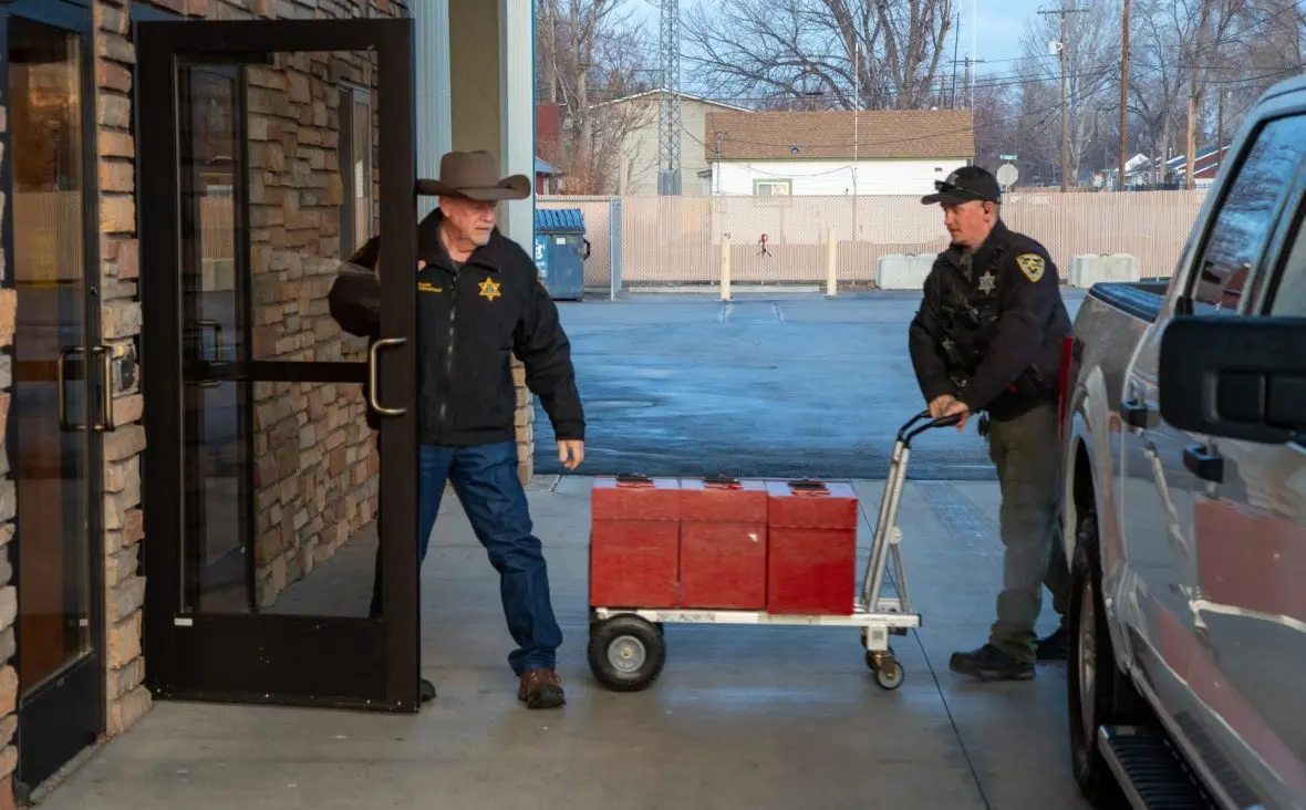 Elmore County Sheriff Mike Hollinshead holds the door open as a deputy brings 3,000 ballots into the Elk’s Lodge in Mountain Home for a hand recount on Monday, Nov. 24, 2025. (Sean Dolan/EdNews)