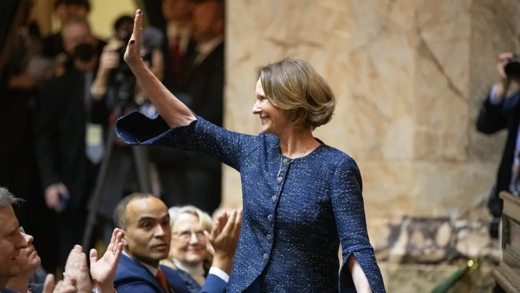 Insurance Commissioner Patty Kuderer waves to the room after being announced during the governor’s inauguration Wednesday, Jan. 15, 2025, at the Washington State Capitol in Olympia, Wash. Kuderer, the state’s first new insurance commissioner in 24 years, was also sworn in on Wednesday. (Photo by Ryan Berry/Washington State Standard)