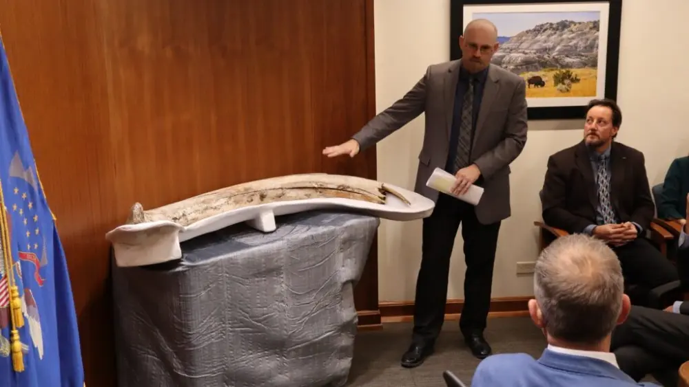 Clint Boyd, North Dakota state paleontologist, shows off a mammoth tusk discovered at a coal mine near Beulah in 2023. He presented the discovery during a Nov. 25, 2025, North Dakota Industrial Commission meeting. (Photo by Jacob Orledge/North Dakota Monitor)