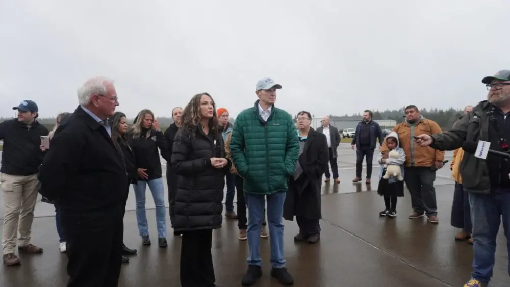 From left to right, Oregon Rep. David Gomberg, D-Otis, Taunette Dixon of the Newport Fishermen’s Wives, and U.S. Sen. Ron Wyden take questions from reporters at the Newport Municipal Airport. (Photo by Shaanth Nanguneri/Oregon Capital Chronicle)