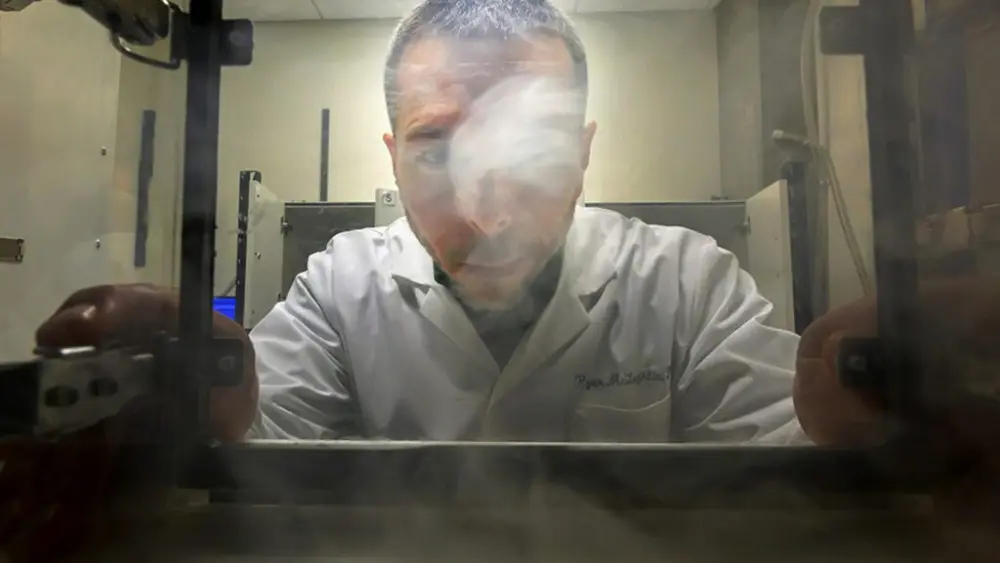 Ryan McLaughlin, an associate professor in the Department of Integrative Physiology and Neuroscience in WSU's College of Veterinary Medicine, looks into a clear box used for cannabis vapor research (photo by Ted S. Warren, College of Veterinary Medicine).