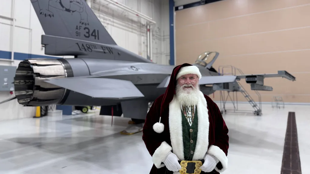 Santa Claus poses for a photo with an F-16 Fighting Falcon assigned to the 148th Fighter Wing, Minnesota Air National Guard, on Dec. 13, 2024. Santa joined children for an evening of fun at a Kid's Holiday Party planned by the 148th Fighter Wing's Airmen and Family Program's Office. (U.S. Air National Guard photo by Audra Flanagan)