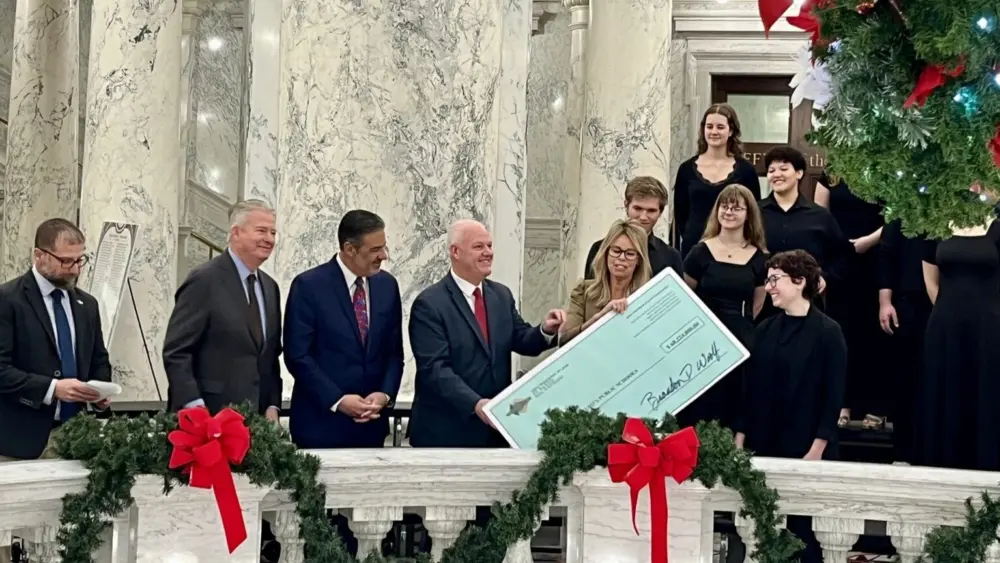 (From left) Idaho Department of Lands Director Dustin Miller, Idaho Gov. Brad Little, Attorney General Raúl Labrador and State Controller Brandon Woolf pass a ceremonial check for Idaho public schools to Superintendent of Public Instruction Debbie Critchfield on Dec. 16, 2025 at the Idaho State Capitol. (Photo by Clark Corbin/Idaho Capital Sun)