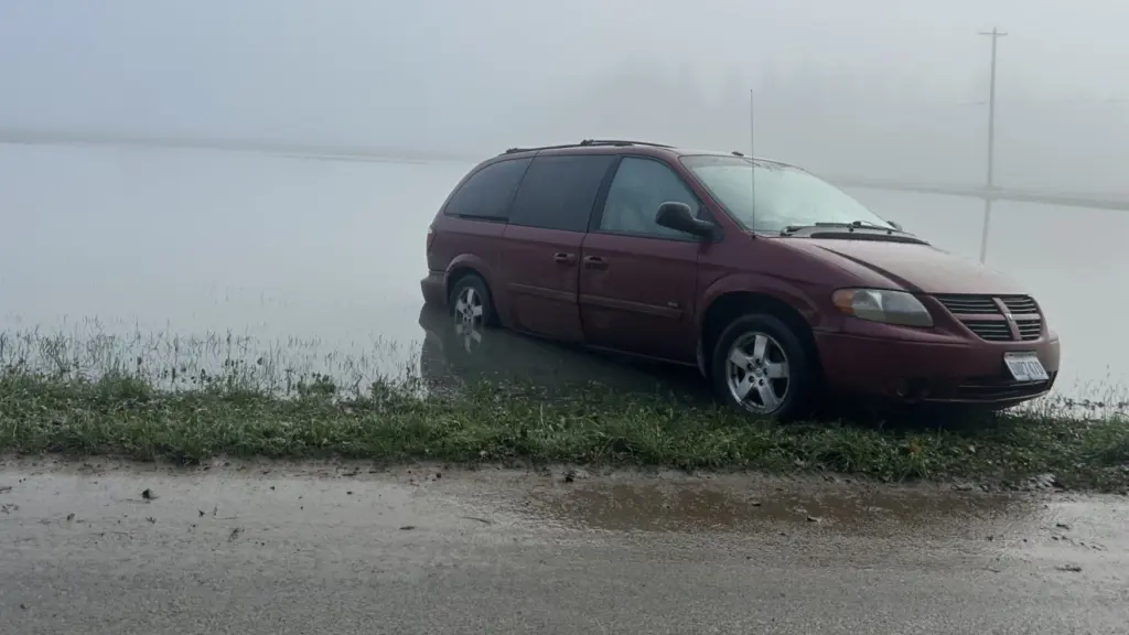 A minivan is stuck after flooding along Tualco Road near Monroe, Washington, on Dec. 13, 2025. The Northwest is seeing warm rains instead of snow in much of the region, concerning climate scientists. (Photo by Jake Goldstein-Street/Washington State Standard)