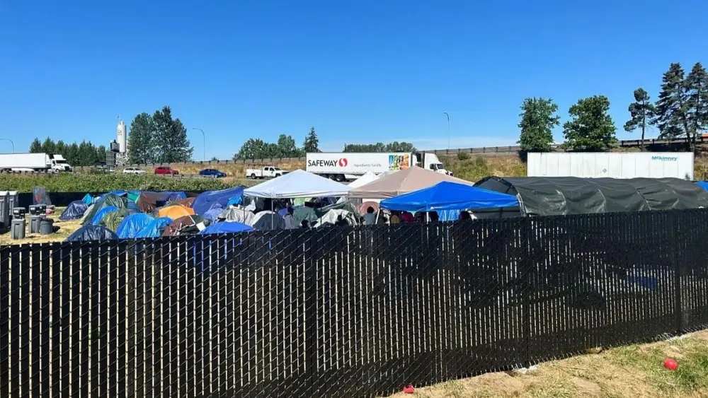 Residents gather behind a fence at a refugee camp in Kent, Wash. Photo: Carleen Johnson / The Center Square