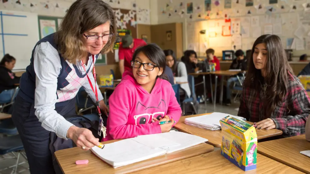 A teacher reviews a student’s work in English class. **THIS IMAGE HAS BEEN DIGITALLY ALTERED TO REMOVE OR OBSCURE STUDENT IDENTITIES.** Photo by Allison Shelley/The Verbatim Agency for EDUimages