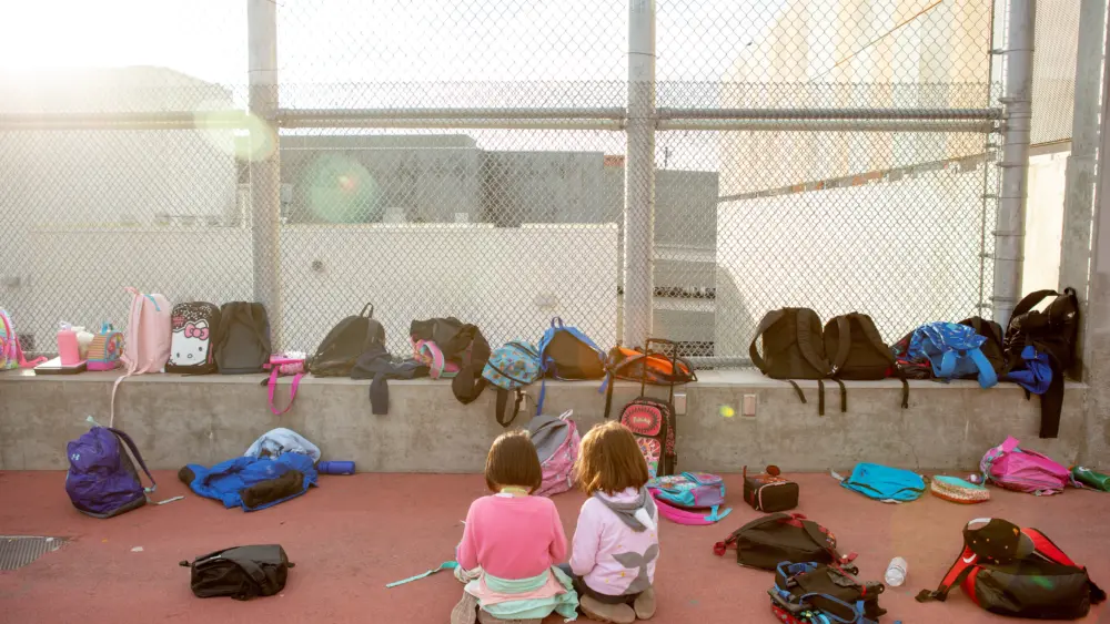 Two kindergarteners read together amid their classmates’ backpacks during an after-school program. Photo by Allison Shelley for EDUimages