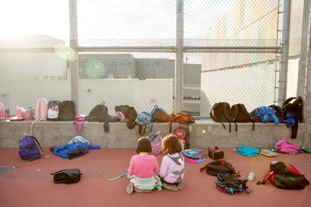 Two kindergarteners read together amid their classmates’ backpacks during an after-school program. Photo by Allison Shelley for EDUimages