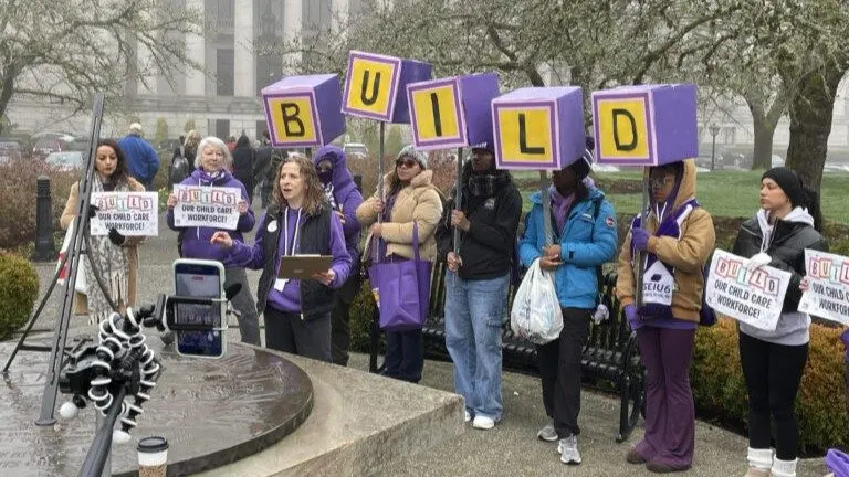 Tricia Schroeder of SEIU Local 925, center, speaks at a Jan. 19, 2026 rally of early learning and child care professionals who seek better wages and benefits and oppose proposed cuts to programs that could leave families with fewer child care options. (Photo by Jerry Cornfield/Washington State Standard)