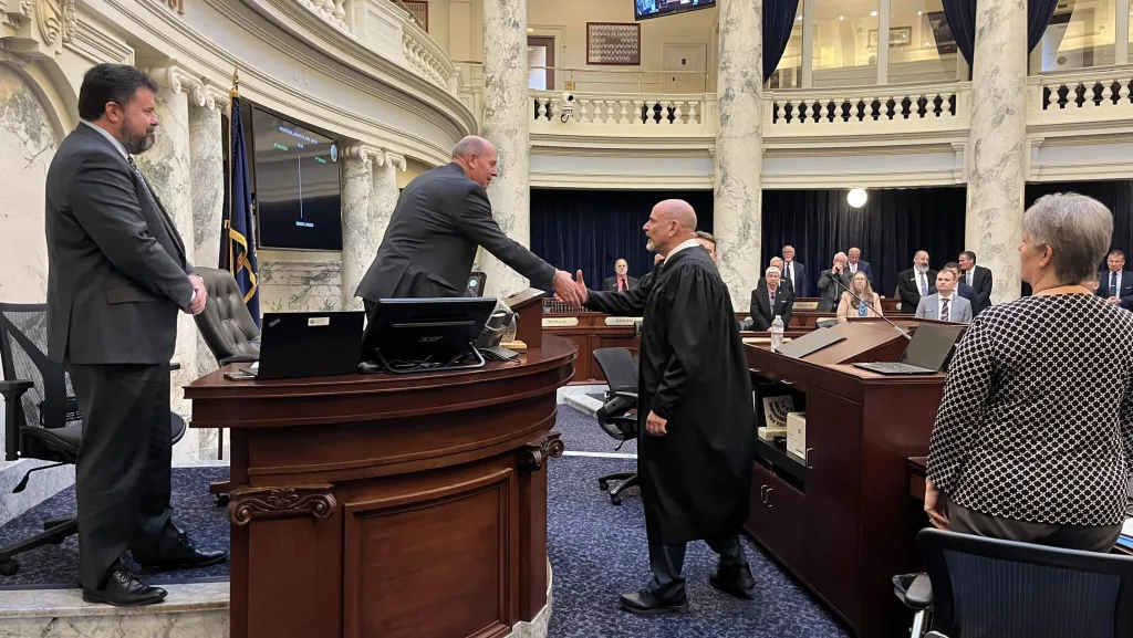 Idaho Supreme Court Chief Justice G. Richard Bevan, standing at center, shakes hands with Idaho House Speaker Mike Moyle, left, after delivering the annual State of the Judiciary address Jan. 21 at the Idaho State Capitol in Boise. (Photo by Clark Corbin/Idaho Capital Sun)