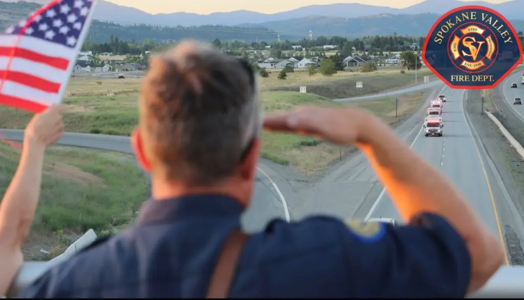 A fellow emergency responder salutes ambulances that joined a procession from Kootenai Health in Coeur d’Alene to Spokane after a gunman opened fire on firefighters responding to a brush fire at Canfield Mountain in North Idaho. (Screenshot courtesy of the Spokane Valley Fire Department)