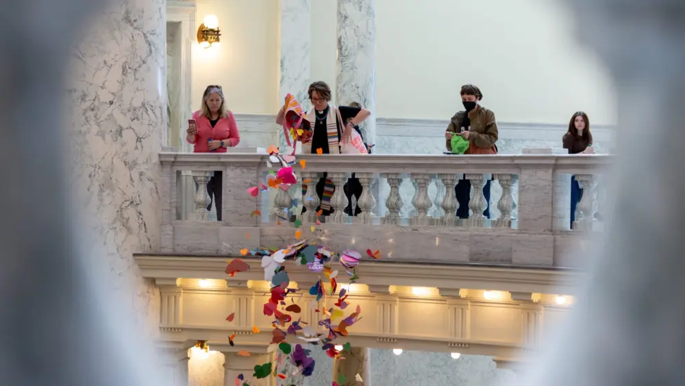 The Rev. Sara LaWall drops hearts down the rotunda of the Idaho State Capitol Building. Protestors on April 2, 2024, dropped 48,000 handmade hearts — meant to represent LGBTQ Idahoans — in protest of anti-LGBTQ legislation. (Kyle Pfannenstiel/Idaho Capital Sun)