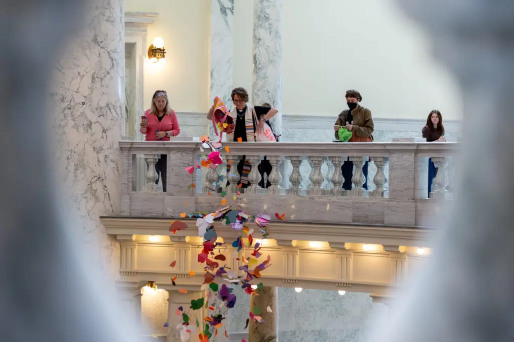 The Rev. Sara LaWall drops hearts down the rotunda of the Idaho State Capitol Building. Protestors on April 2, 2024, dropped 48,000 handmade hearts — meant to represent LGBTQ Idahoans — in protest of anti-LGBTQ legislation. (Kyle Pfannenstiel/Idaho Capital Sun)