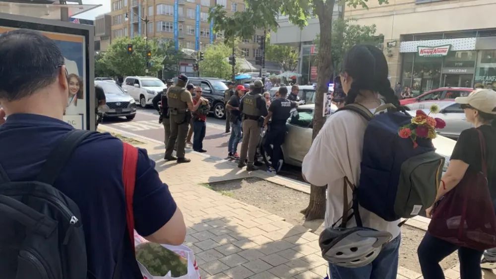 Bystanders watch as Washington, D.C., police and agents from the federal Drug Enforcement Administration make an arrest in August. Crime in major U.S. cities continued to decline in 2025, with homicides down 21% from 2024 and 44% from a peak in 2021, according to a new analysis by the Council on Criminal Justice. (Photo by Noelle Straub/Stateline)