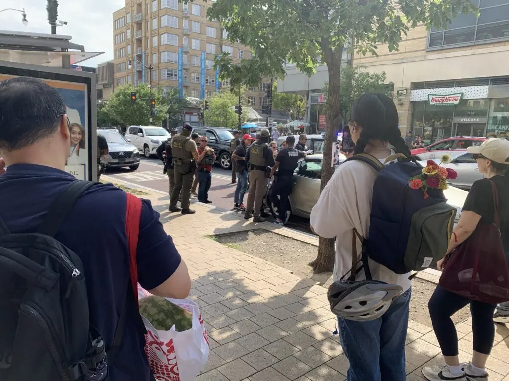 Bystanders watch as Washington, D.C., police and agents from the federal Drug Enforcement Administration make an arrest in August. Crime in major U.S. cities continued to decline in 2025, with homicides down 21% from 2024 and 44% from a peak in 2021, according to a new analysis by the Council on Criminal Justice. (Photo by Noelle Straub/Stateline)