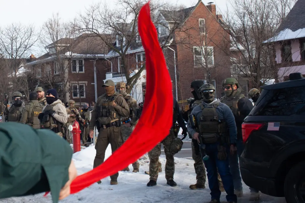 A demonstrator waves a red cloth as hundreds gather after ICE agent Jonathan Ross shot and killed Renee Good through her car window Wednesday, Jan. 7, 2026 near Portland Avenue South and East 34th Street in Minneapolis. (Photo by Nicole Neri/Minnesota Reformer)