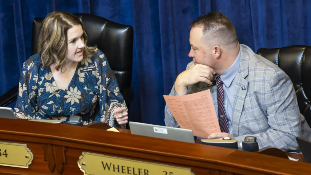 Reps. Britt Raybould, R-Rexburg, (left) and Josh Wheeler, R-Ammon, chat before a floor session in the House on March 10, 2025, at the Idaho Capitol Building in Boise. (Pat Sutphin for the Idaho Capital Sun)
