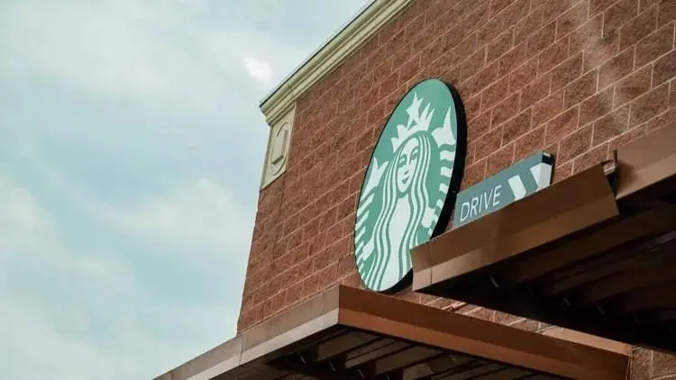 A Starbucks Coffee sign and drive-thru sign are displayed on the side of a brick building. Photo: Grace David / The Center Square