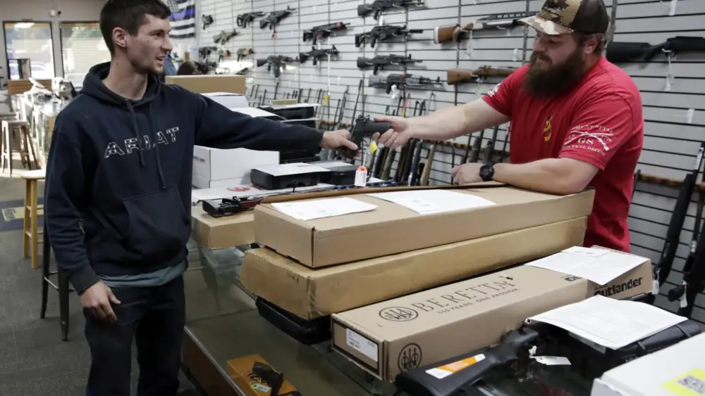 Customer Matt Schonbachler (left) of Scotts Mills, hands a handgun back to assistant manager Trent Bergerson at Tick Licker Firearms in Salem on Friday, Nov. 18, 2022. Sales have been brisk since voters passed Measure 114, tightening Oregon’s gun laws. (Photo by Connor Radnovich/Oregon Capital Chronicle)