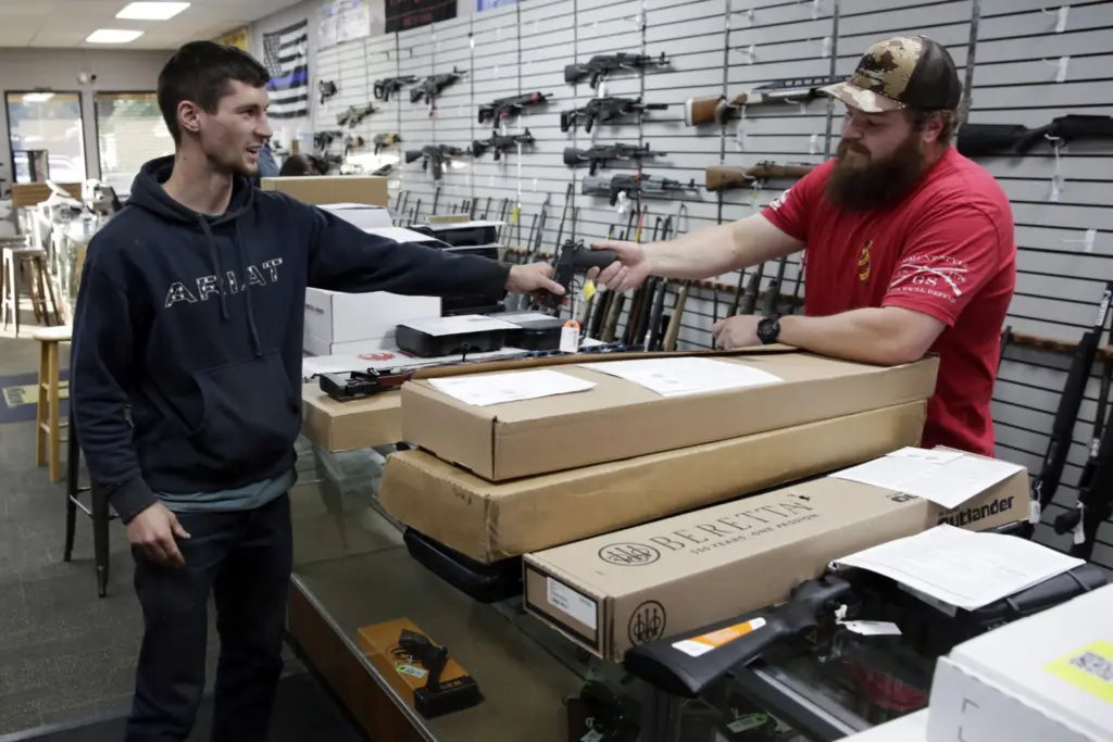 Customer Matt Schonbachler (left) of Scotts Mills, hands a handgun back to assistant manager Trent Bergerson at Tick Licker Firearms in Salem on Friday, Nov. 18, 2022. Sales have been brisk since voters passed Measure 114, tightening Oregon’s gun laws. (Photo by Connor Radnovich/Oregon Capital Chronicle)