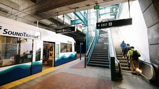 A Sound Transit Link light rail train is stopped at a station as riders use the stairs and escalator to exit. Photo: Carleen Johnson / The Center Square