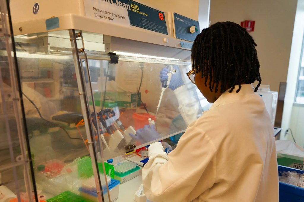 Dora Nabatanzi, a molecular biologist at the Broad Institute, prepares chemicals needed to sequence the genomes of measles viruses. (Amy Maxmen/KFF Health News)