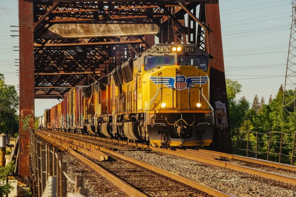 A Union Pacific freight train hauls cargo containers across a steel bridge on a sunny day. Photo: Vitaliy Haiduk / Pexels