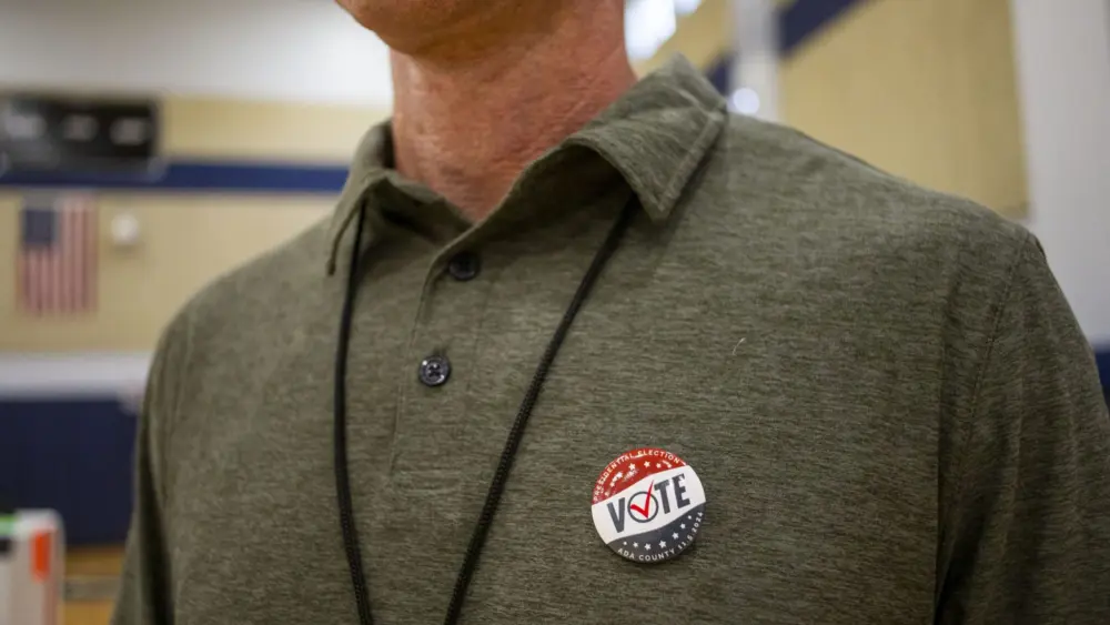 A poll worker proudly displays his vote button while working the general election on Nov. 5, 2024, at North Junior High in Boise. (Pat Sutphin for the Idaho Capital Sun)