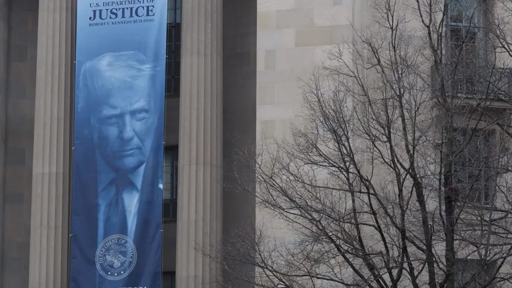 A banner showing President Donald Trump hangs on the Robert F. Kennedy Building of the U.S. Department of Justice on Feb. 20, 2026. (Photo by Shauneen Miranda/States Newsroom)