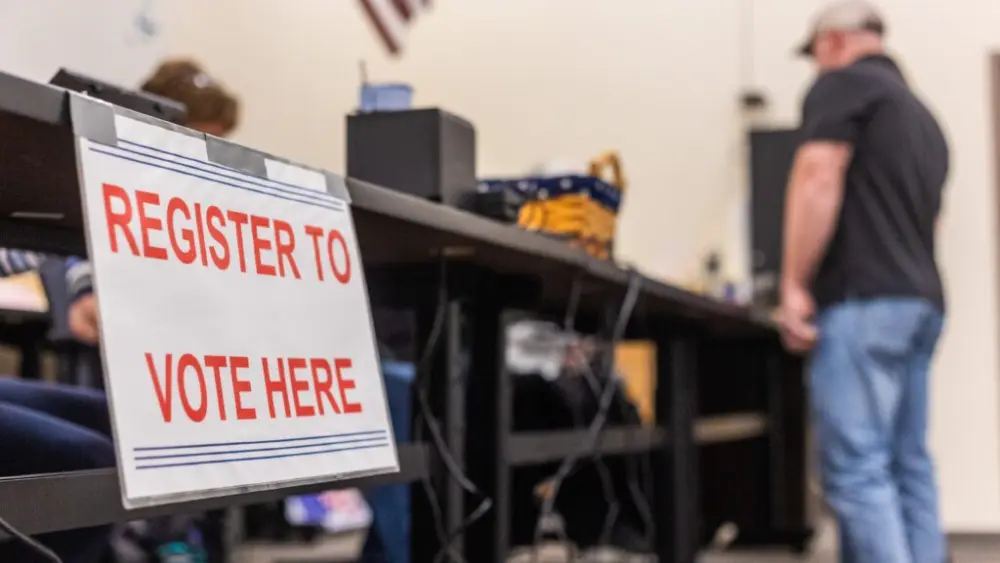 Poll workers help voters register to vote for the primary election on May 21, 2024, at Thunder Ridge High School in Idaho Falls. (Photo by Pat Sutphin for the Idaho Capital Sun)