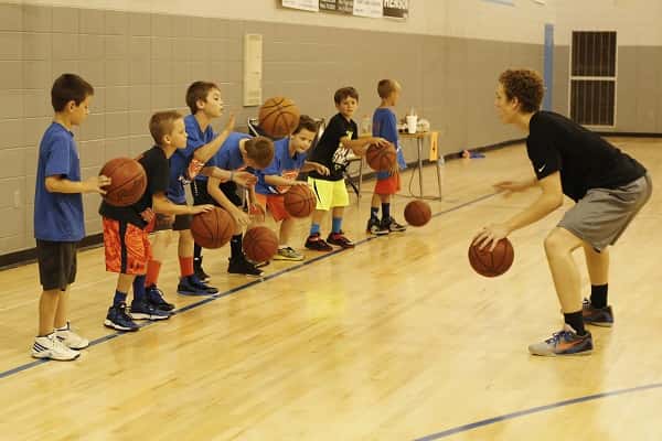 Marshals varsity player, Dylan Walters, leads a group of campers in a dribbling drill.