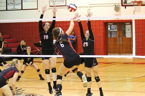 Rebekah Muller (19) and Abigail Cima (23) working to block a hit by Alyssa McKinney (6).