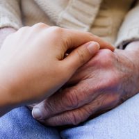 young-caregiver-holding-seniors-hands