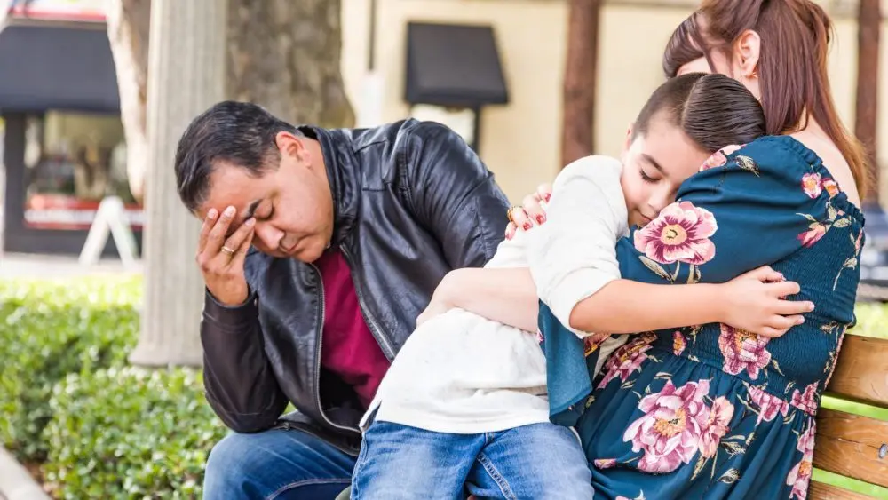caucasianmotherandhispanicfathercomfortingmixedracesonoutdoors