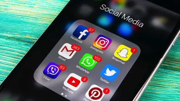 smartphone-with-icons-of-social-media-on-screen-on-wooden-table-smartphone-life-style-smartphone-starting-social-media-app-office-shot