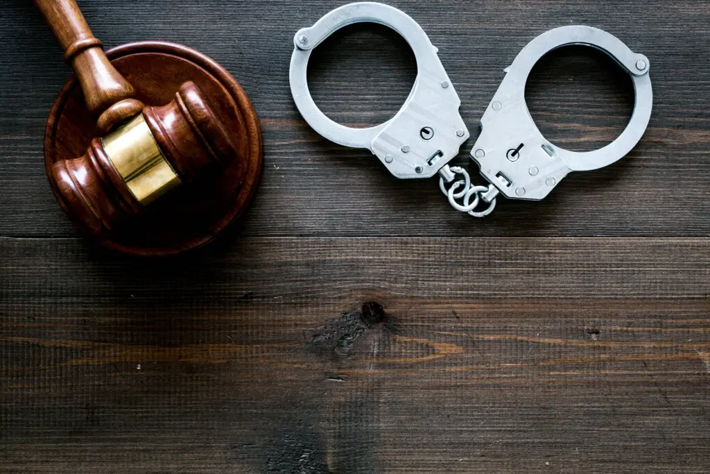 arrestconcept-metalhandcuffsnearjudgegavelondarkwooden