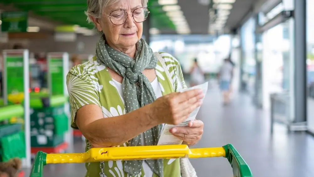 seniorwomaninthesupermarketcheckshergroceryreceiptlooking