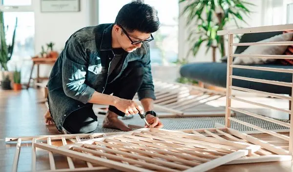 young-father-assembling-baby-cot-at-home
