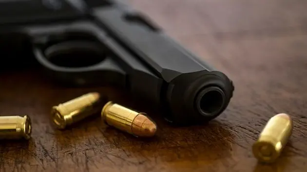 gold-bullets-and-pistol-on-wooden-surface