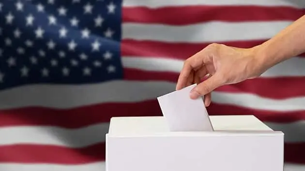 close-up-of-man-casting-and-inserting-a-vote-and-choosing-and-making-a-decision-what-he-wants-in-polling-box-with-united-states-flag-blended-in-background