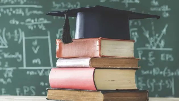 stack-books-graduate-hat-in-front-of-green-chalkboard