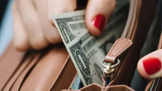 the-girls-hand-takes-out-paper-dollars-from-a-leather-orange-purse-crisis-and-economy-concept-close-up