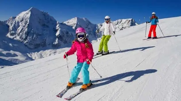 young-family-skiing-down-a-snowy-slope